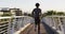 Rear view of fit african american man exercising outdoors in city, running on footbridge