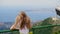 Rear view of girl leaning at railing and looking at coastal town