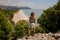 Rear view girl in the light dress standing on the rock on the seacoast