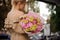 Rear view of girl who holds bouquet with flowers of different colors.