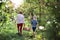 A rear view of grandmother with grandson carrying wooden box with apples in orchard.