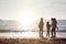 Rear View Of Grandmother With Mother And Granddaughters Standing Silhouetted By Sea