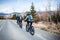 Rear view of group of mountain bikers riding on road outdoors in winter.