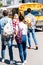 rear view of group of teen casual students with backpacks walking to school bus