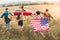 rear view of group of young american travellers with flag walking by flower field during