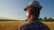 rear view of a human head senior farmer looks at and examines the agricultural field
