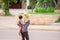 Rear view of Khmer mother holding son in her arms while across a street near construction site. Phnom Penh, Cambodia