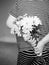 Rear view of kid with bunch of beautiful yellow Chrysanthemum behind his back in black and white, Child in pajamas holds flowers b