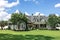 The rear view of a large gray craftsman new construction house with a landscaped yard and a garage and driveway