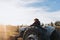 Rear view of a latin farmer woman driving an old tractor, in the middle of his farmland at sunset