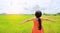 Rear view of little Asian child girl stretch arms and relaxed at the young green paddy fields with morning sunlight