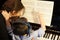 Rear view of a little boy learning piano from