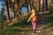 Rear view of little girl in warm clothes that walks on footpath in forest