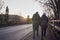 Rear View Of Loving Senior Couple Enjoying Autumn Or Winter Walk Along Road By Bridge