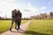 Rear View Of Loving Senior Couple Enjoying Autumn Or Winter Walk Through Park Together