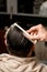 rear view of male head with wet hair and hand of barber gently combing hair