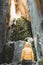 Rear view of male hiker standing next to large red stone cave