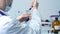 Rear view of male scientist doctor injecting chemicals into test tubes and holding three test tubes with blue substance