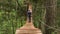 Rear view of male tourist crossing wooden suspension bridge in green forest. Stock footage. Back view of a man walking