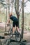 rear view of male trial biker in protective helmet riding on mountain bicycle on stones