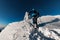 rear view of a man in a bright ski suit with ski poles climbing up a snow trail