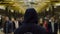 Rear view of a man with a dark blue hoodie on standing in front of a crowd at the station, resistance concept. Close up