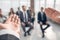 Rear view of a man gesticulating with his hand while standing against a defocused group of people