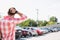 Rear view of man with hand behind head standing on city street against clear sky