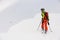 rear view of man skier with trekking poles walking along snowy mountain slope