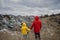 Rear view of man with small child standing on landfill, environmental concept.