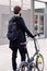 Rear view of a man walking with a folding bike