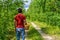 Rear view of man with wicker basket filled with aspen mushrooms. Mushroom picker walking alone country road against summer