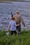 Rear View On Mature Grandfather And Grandson Going To Fish On Riverside in Countryside