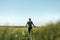 Rear view of middle-aged farm worker wearing green trucker hat and t-shirt walking through cultivated barley crops field on sunny