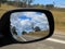 Rear view mirror of car reflecting Australian countryside