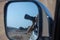 Rear view mirror photo of girl taking a picture in the desert with a large zoom lens