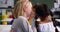 Rear view of mixed-race schoolgirl whispering in her classmates ear at classroom 4k