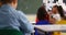 Rear view of mixed-race schoolgirls whispering in her classmates ear at classroom 4k