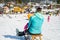 Rear view of mother and daughter rushing down slope on a sledge.