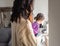 Rear view of mother with daughter sitting by the window with Christmas decorations, waiting for a miracle. Beautiful Caucasian