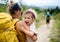 Rear view of mother with small crying daughter hiking outdoors in summer nature.