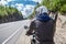 Rear view of motorcyclist stopped on roadside. Sitting on bike in leather outfit