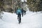 Rear view of mountain bikers riding on road in forest outdoors in winter.