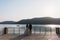 Rear view newlyweds couple, bride and groom holding hands on a lake background. Cute girl in white dress, men in black