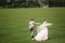 Rear view, newlyweds are walking along the green field of the golf club on a wedding day. The bride and groom in wedding