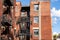 Rear view of an old apartment building with black steel fire escapes and balconies