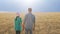 Rear view of a pair of young farmers agronomists standing in the background of a wheat field.