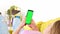 Rear view of phone with green screen chroma key in hands of blonde in pink top. Mockup concept for inserting your