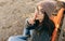 Rear view portrait of beautiful young brunette woman wearing eyeglasses, knitted sweater and hat making silent gesture. Outdoor