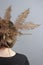 Rear view portrait of brunette girl with crown of fern in her hair, gray background. Stylish Hairstyle with Golden Umbrella Fern